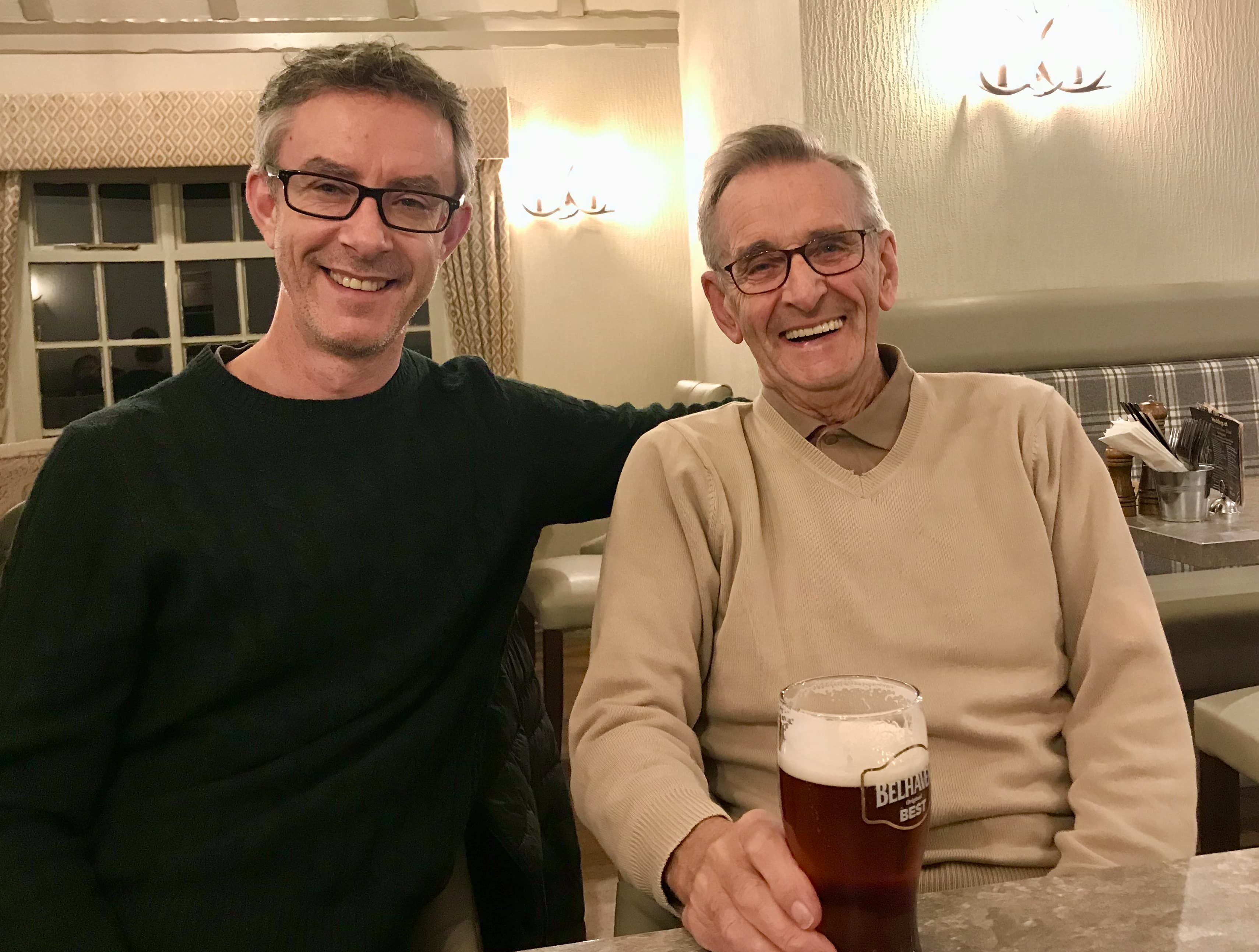 Steve Scott with his father, David, both smiling in a pub with a pint on the table between them.